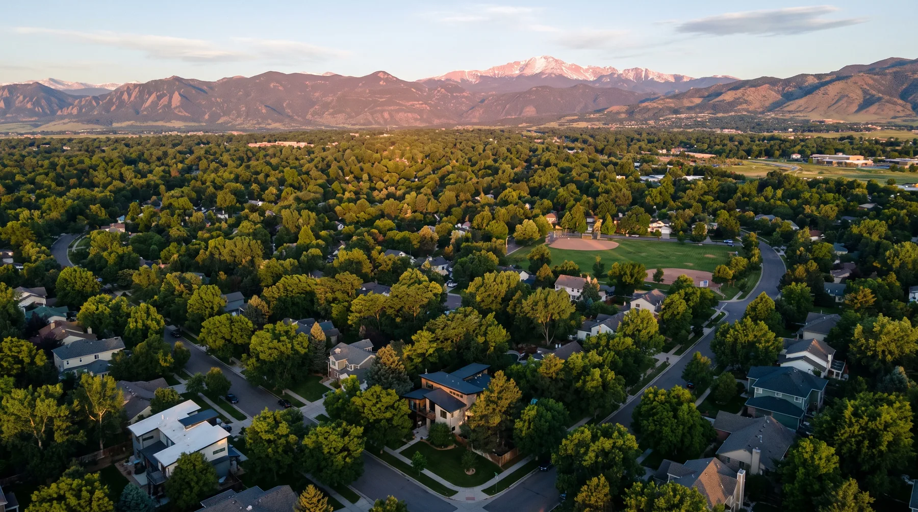 Aerial view of Longmont neighborhoods under alpenglow with the Front Range beyond